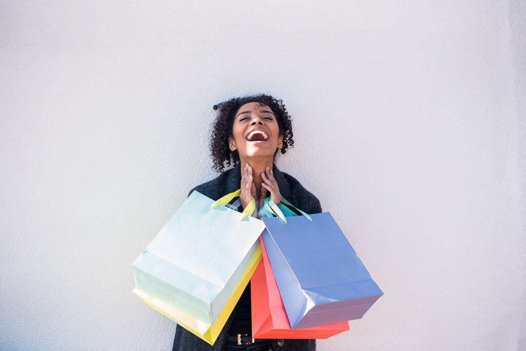 mulher sorrindo com sacolas de compras nas mãos, representando os brindes de natal para clientes